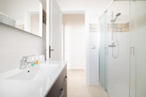 y baño blanco con lavabo y ducha. en Casa Beatrice, en Caprarica di Lecce