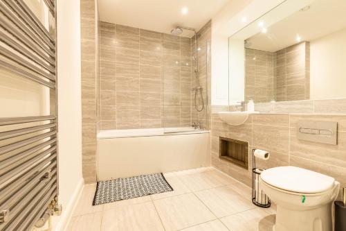 a bathroom with a tub and a toilet and a sink at Comfy 2-Bed Flat in Dartford, Kent. in Kent