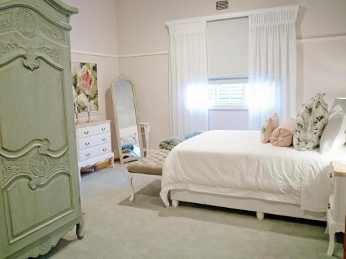 Schlafzimmer mit einem Bett, einer Kommode und einem Spiegel in der Unterkunft The Sweet Rose in Bloemfontein
