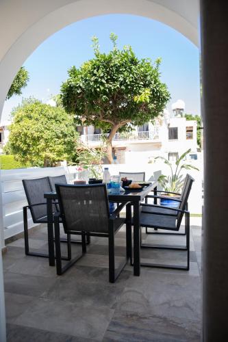 a table and chairs on a patio with a tree at Taheli Riverside Townhouse in Tourist Area in Paphos