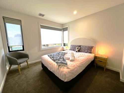 a bedroom with a bed and a chair and two windows at Altona entire 3 bedrooms house in Altona