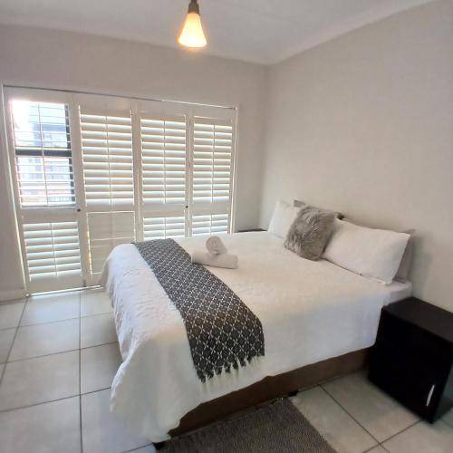 een slaapkamer met een groot bed en een groot raam bij The Luxe Marvelous Apartment in Pretoria