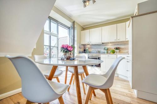a kitchen with a table and white chairs at 54 Grad Nordost in Zingst