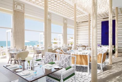 a restaurant with white tables and chairs and the ocean at Jumeirah Saadiyat Island Abu Dhabi in Abu Dhabi