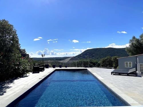 une piscine dans une arrière-cour avec des montagnes en arrière-plan dans l'établissement Villa Alteto magnifique vue mer, piscine, à Zonza