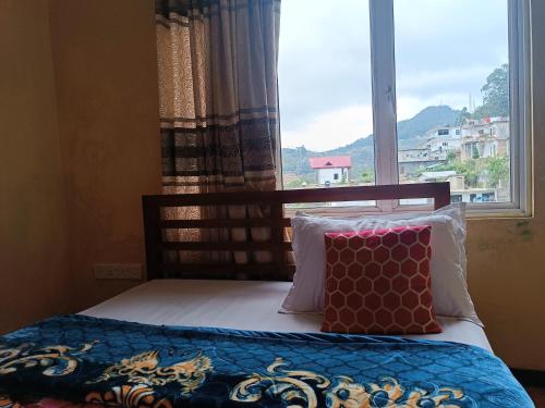 a bed with two pillows in front of a window at Hakuna Matata in Nuwara Eliya