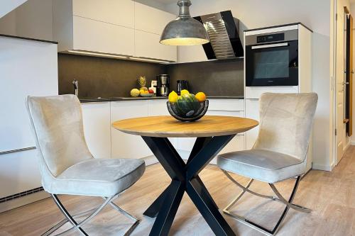 een keuken met een tafel met 2 stoelen en een fruitschaal bij Düne 7 Apartment 7A 05 in Zingst