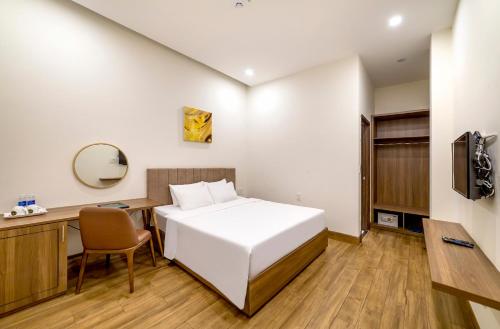 a bedroom with a bed and a desk and a mirror at TALA Dalat Hotel in Da Lat