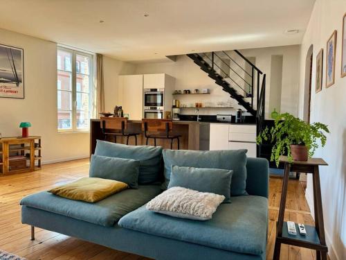 un sofá azul en una sala de estar con cocina en Le Canadair, Grand T2 lumineux, en Montauban
