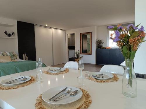 un tavolo bianco con piatti e un vaso di fiori di Spacious Studio by the University a San Vicente del Raspeig
