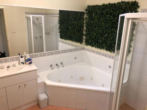 La salle de bains est pourvue d'une baignoire blanche et d'une haie verte. dans l'établissement 225 on Myall, à Tea Gardens