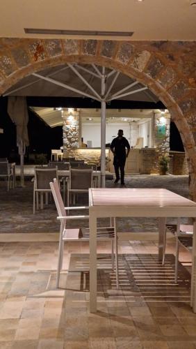 a man standing under an umbrella in a restaurant at Castello Antico Hotel in Gythio