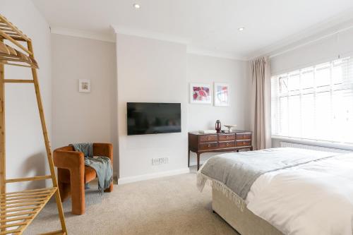 een slaapkamer met een bed, een tv en een stoel bij Spacious 4 bedroom home - sleeps 8 in Manchester