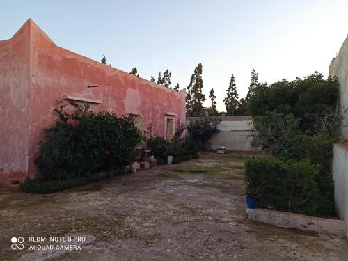 an old red building with bushes next to a yard at Villa tradesionelle in Ghazoua