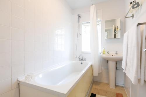 een witte badkamer met een bad en een wastafel bij Spacious 4 bedroom home - sleeps 8 in Manchester