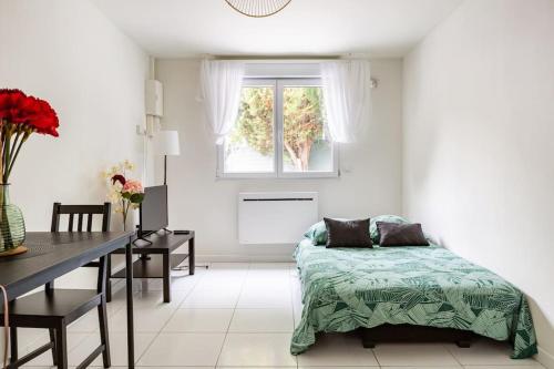 Schlafzimmer mit einem Bett, einem Tisch und einem Fenster in der Unterkunft studio lumineux in Choisy-le-Roi