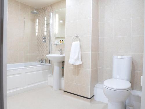 La salle de bains est pourvue de toilettes, d'un lavabo et d'une baignoire. dans l'établissement Cambridge Hotel Waterfront, à Brighouse