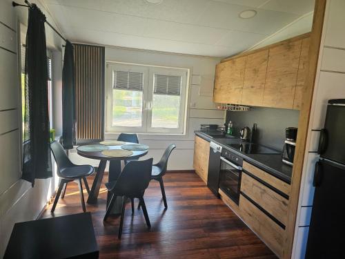 a kitchen with a table and chairs and a kitchen with a counter at Domek letniskowy zielony-całoroczny in Stegers