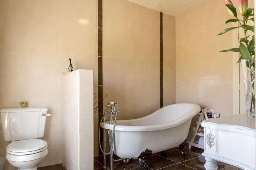 a bathroom with a tub and a toilet and a sink at Doleen House in Ballyconneely