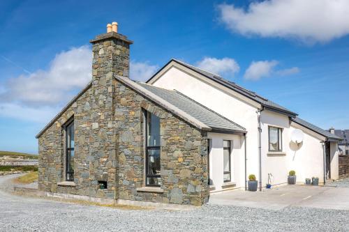 a stone house with a chimney on top of it at Doleen House in Ballyconneely