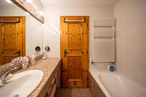 a bathroom with a tub and a sink and a mirror at Chasa Munt Plan in Scuol