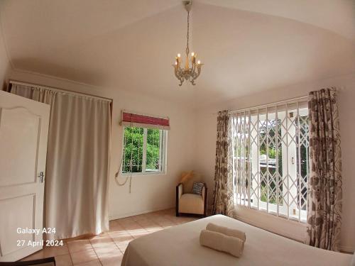 a bedroom with a bed and a window and a chandelier at The Coral House in Rivière Noire