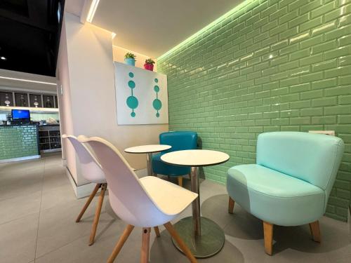a restaurant with two tables and chairs and a green brick wall at Onmood Cala Ratjada - Bed & Brunch in Cala Ratjada