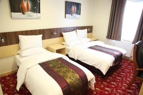 a hotel room with two beds and a window at Cambridge Hotel Waterfront in Brighouse