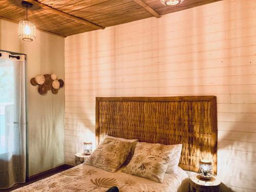 Schlafzimmer mit einem großen Bett mit einem Kopfteil aus Holz in der Unterkunft Mika & Clo in Saint-Joseph
