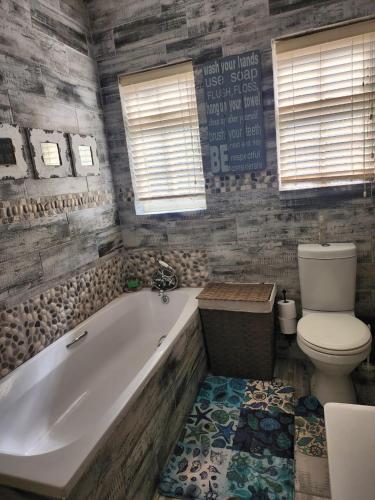 a bathroom with a tub and a toilet at 16 on Main Arniston PET-FRIENDLY in Arniston