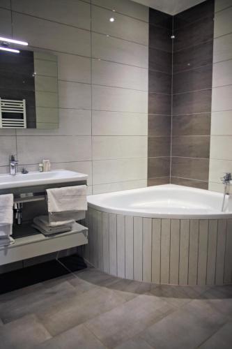 une salle de bain avec une baignoire et un lavabo dans l'établissement Hotel-Restaurant St-Christophe, à Belfort