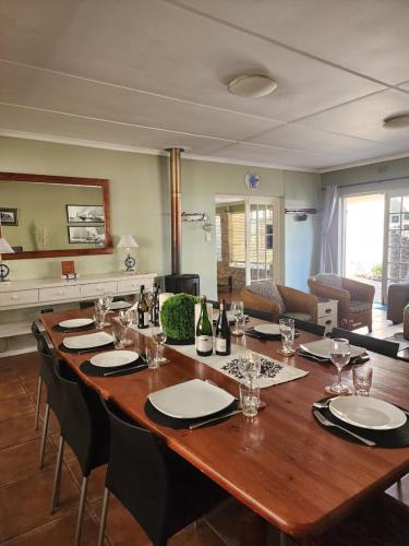 a large wooden table with chairs and wine bottles on it at 16 on Main Arniston PET-FRIENDLY in Arniston