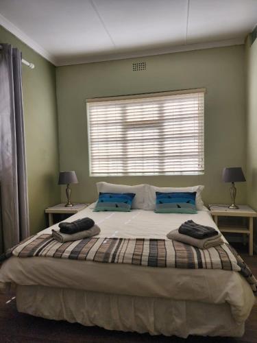 a bedroom with a large bed with blue pillows at 16 on Main Arniston PET-FRIENDLY in Arniston