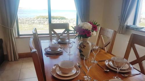 a dining room table with a vase of flowers on it at Coral Strand Lodge in Ballyconneely