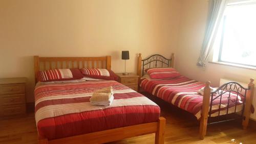 a bedroom with two beds and a window at Coral Strand Lodge in Ballyconneely
