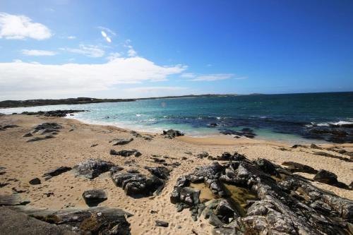 a sandy beach with rocks and the ocean at Coral Strand Lodge in Ballyconneely