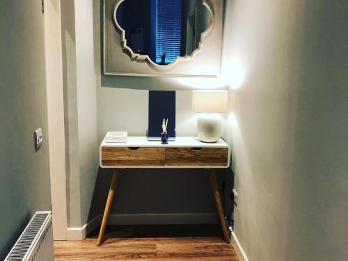 a bathroom with a table with a lamp and a mirror at The Lane Apartment in Edinburgh