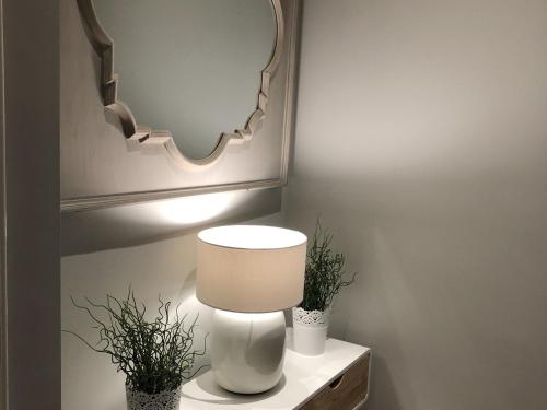 a white lamp on a table with two plants at The Lane Apartment in Edinburgh