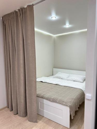 - une chambre avec un lit et un rideau dans l'établissement 1 комнатная квартира, Уральск, à Uralsk