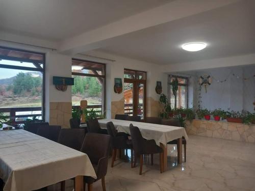 uma sala de jantar com mesas, cadeiras e janelas em La Lacuri em Sovata