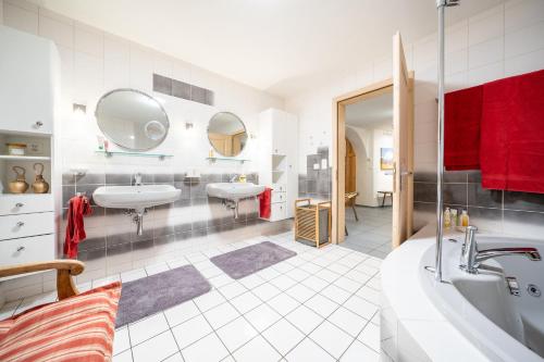 a bathroom with two sinks and two mirrors at Chasa Curtin 17 in Sent