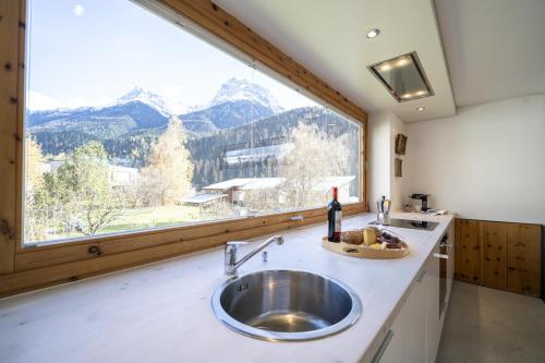 a kitchen with a sink and a large window at Chasa 5 in Scuol