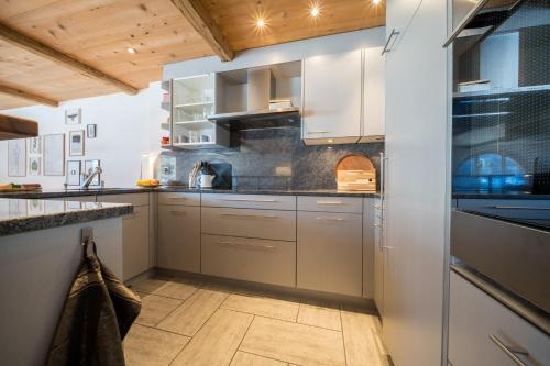 a kitchen with stainless steel appliances and wood ceilings at Chasa Pro la Tuor in Ardez