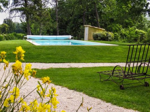 a bench sitting in the grass near a swimming pool at La Moutière in Colonzelle