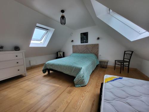 um quarto com uma cama e uma cadeira num sótão em 375- Villa Ker Goulien a 100m de la plage em Crozon