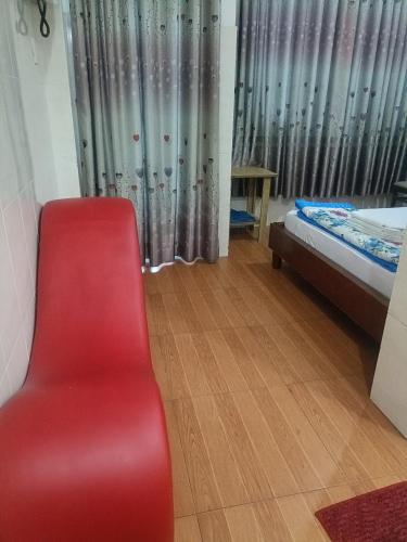 a red chair in a room with a bed and a window at Hotel Phương linh in Ho Chi Minh City