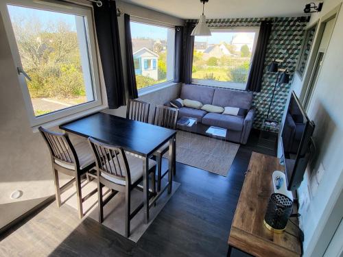 un salon avec une table, des chaises et un canapé dans l'établissement 714-Ker Tiny a 300m de la mer et du GR34, à Plouhinec