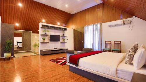 een slaapkamer met een bed en een televisie in een kamer bij The Grand Retreat - Chikmagalur in Chikmagalūr