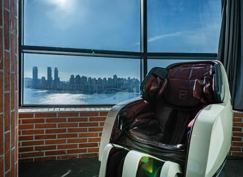 a suitcase sitting in a chair in front of a window at H Avenue Hotel Gwangalli branch in Busan