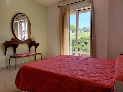 een slaapkamer met een bed, een spiegel en een raam bij Vivienda Turística Ronda del Carmen in Bujalance